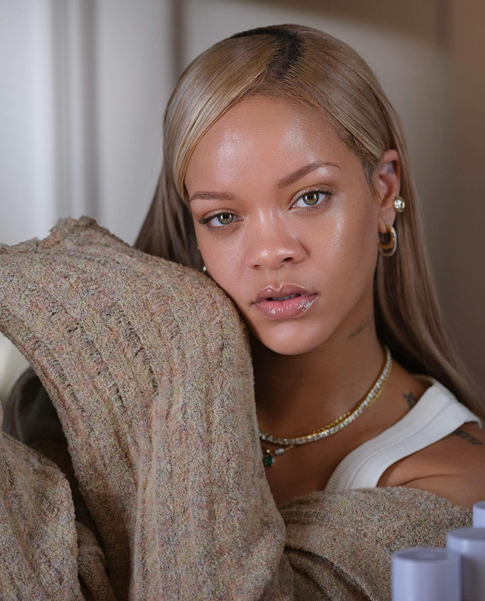 Rihanna wearing casual attire and jewelry, leaning on a textured sweater. Rihanna wearing casual attire and jewelry, leaning on a textured sweater.