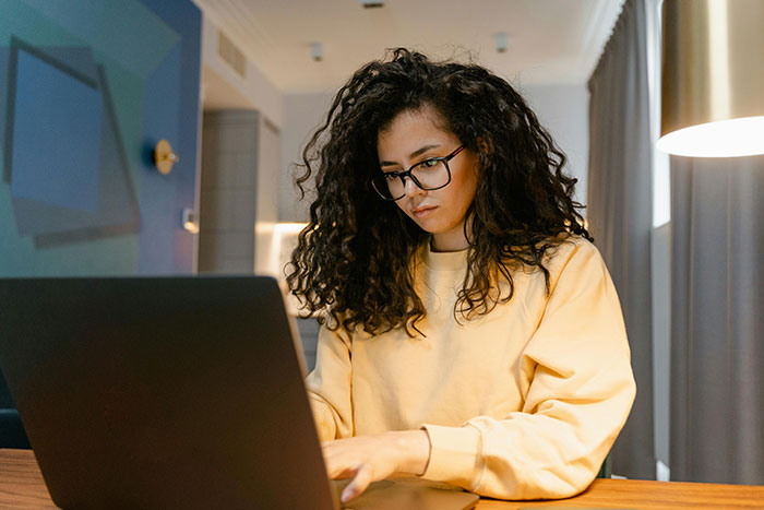 Woman in glasses using a laptop in a cozy room, representing discussion on HIV status impact on relationships. Woman in glasses using a laptop in a cozy room, representing discussion on HIV status impact on relationships.