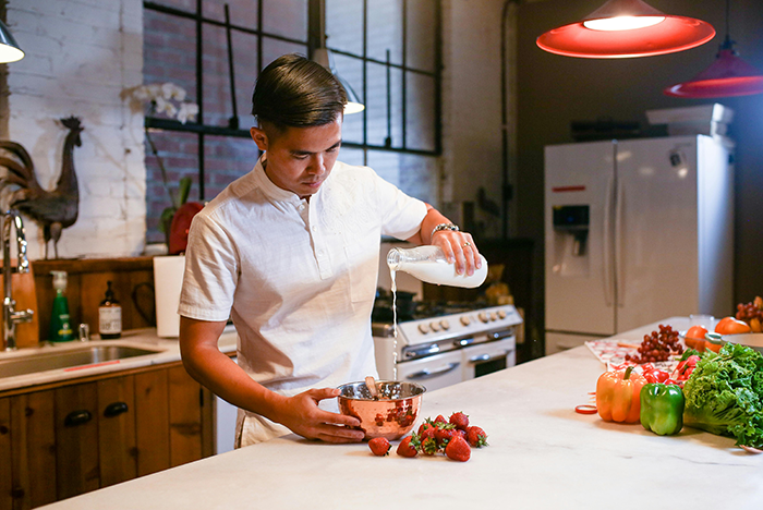 Man cooking in a kitchen, preparing food with fresh ingredients on the counter.