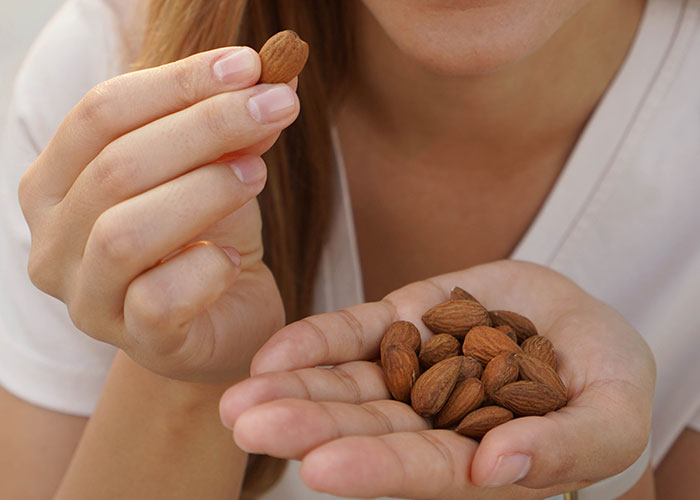 Woman holding almonds, a food allergy revenge tactic.