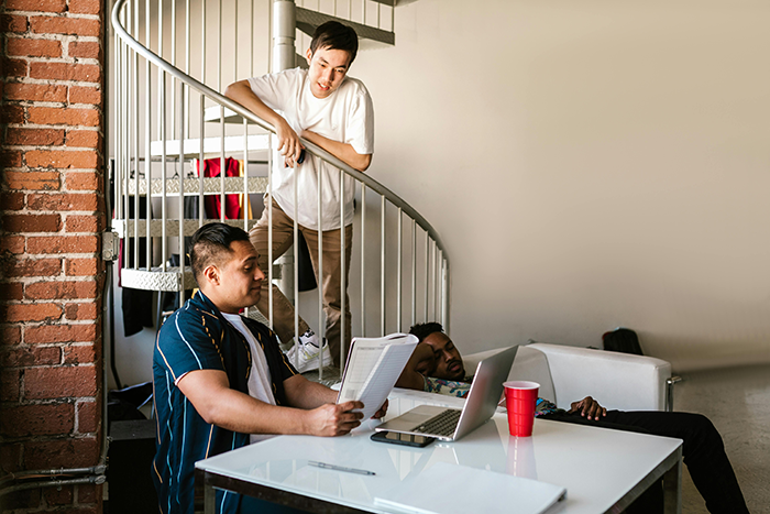 Roommates in a casual setting, one using a laptop at a white table, related to a mozzarella prank story. Roommates in a casual setting, one using a laptop at a white table, related to a mozzarella prank story.