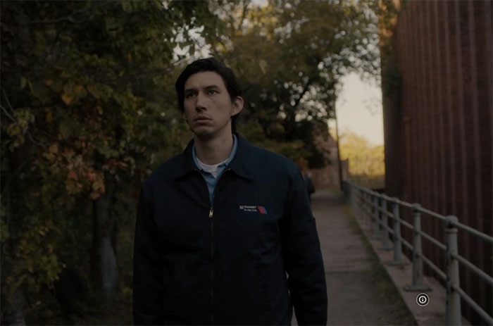 Man in a dark jacket walking along a path surrounded by trees and buildings; illustration for rude celebrity encounters discussion.