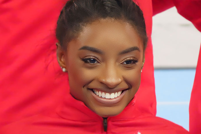 Smiling celebrity in a red outfit, indoors.