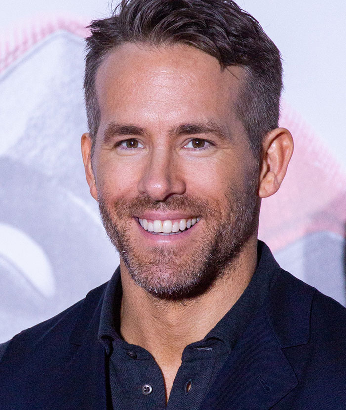 A smiling man in a dark shirt and jacket, related to the topic of rude celebrities.