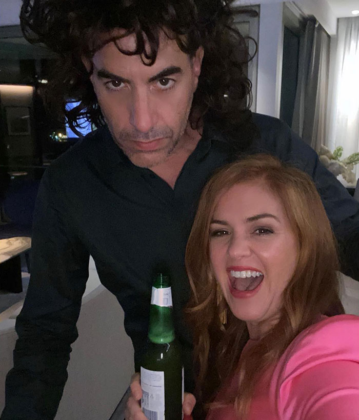 Man and woman smiling in a casual setting, holding a drink; keywords: Sacha Baron Cohen, Isla Fisher, divorce. Man and woman smiling in a casual setting, holding a drink; keywords: Sacha Baron Cohen, Isla Fisher, divorce.