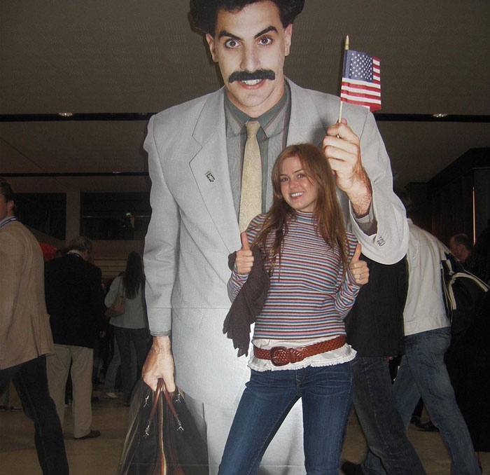 Woman posing with Sacha Baron Cohen cardboard cutout, casually dressed, smiling, indoors. Woman posing with Sacha Baron Cohen cardboard cutout, casually dressed, smiling, indoors.