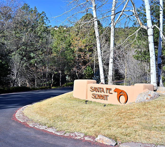 Santa Fe Summit entrance sign with trees and road in the background.