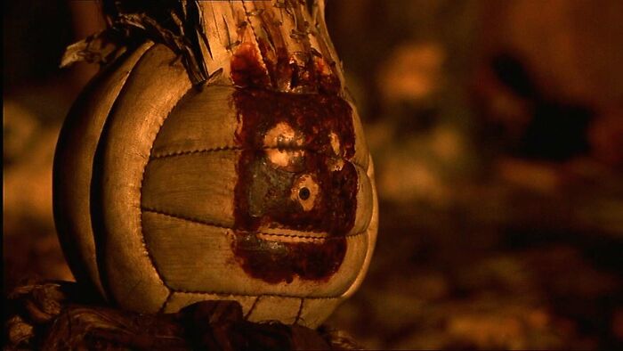 A weathered volleyball with a handprint face from a famous movie prop story, lit warmly in a dark setting.
