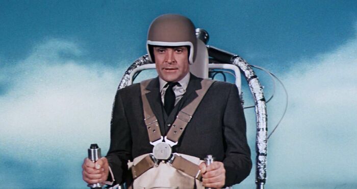 Person in a jetpack gear against a cloudy sky, highlighting famous movie props.