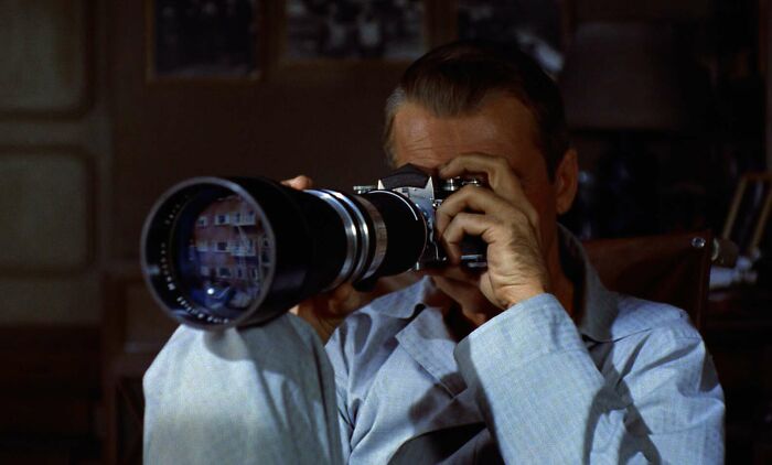 Person using a large camera lens, representing famous movie props stories.