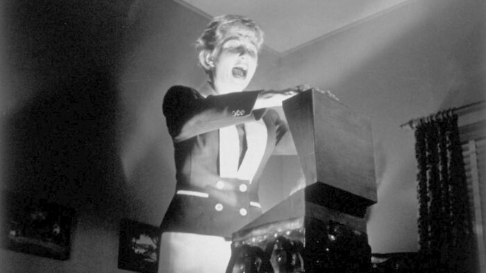 Person in a dramatic scene with a glowing box, related to famous movie props stories.