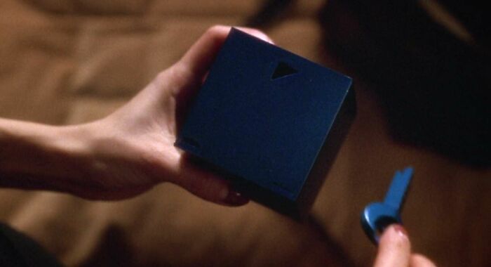 Hands holding a blue box and key from a famous movie prop.