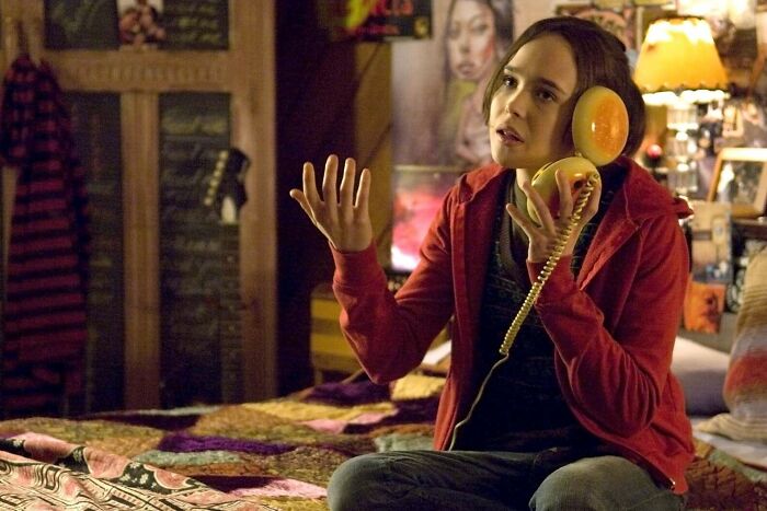 Person holding a hamburger phone, famous movie prop, in a bedroom setting with posters.