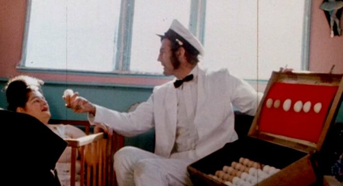 Person in a white suit with a box of eggs, illustrating a scene linked to famous movie props stories.