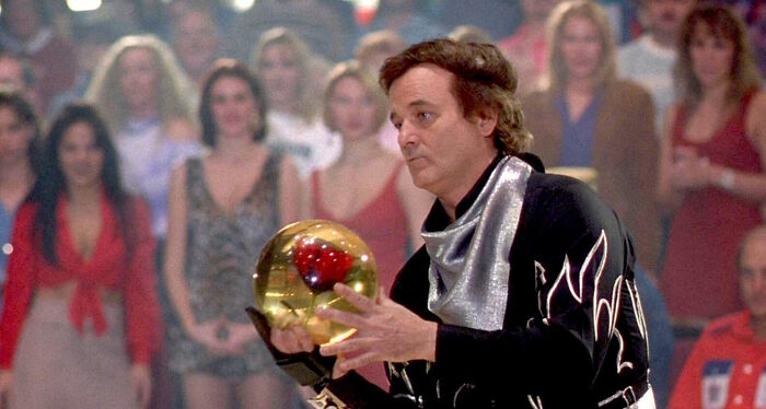 Man in a flashy bowling outfit holding a golden bowling ball.