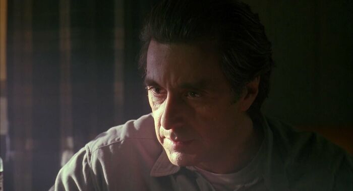 Man in 90s-style lighting, looking serious, with a softly lit background, symbolizing celebrities in the 90s.