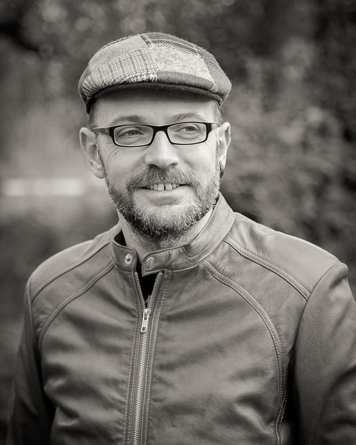 Dr. C&eacute;dric Sueur outdoors wearing a cap and glasses, dressed in a leather jacket, smiling.