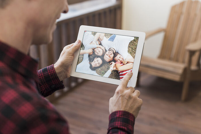 Person holding a tablet with a family photo; a perfect gift idea for someone who has everything.