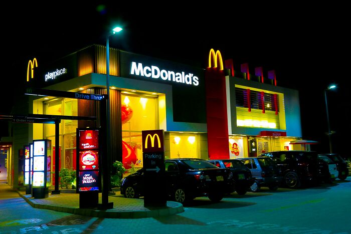McDonald's restaurant at night with cars parked outside, showcasing a popular workplace scene in retail and food service.