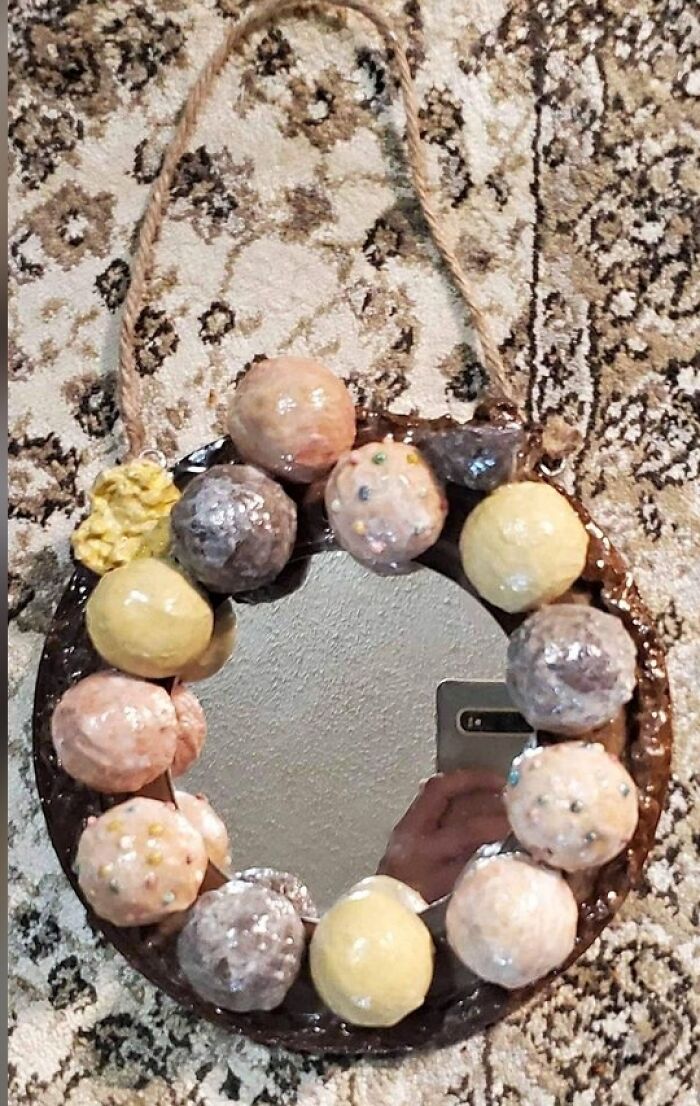 Mirror with colorful, uneven clay balls and a rope hanger, showcasing a DIY craft shaming project.