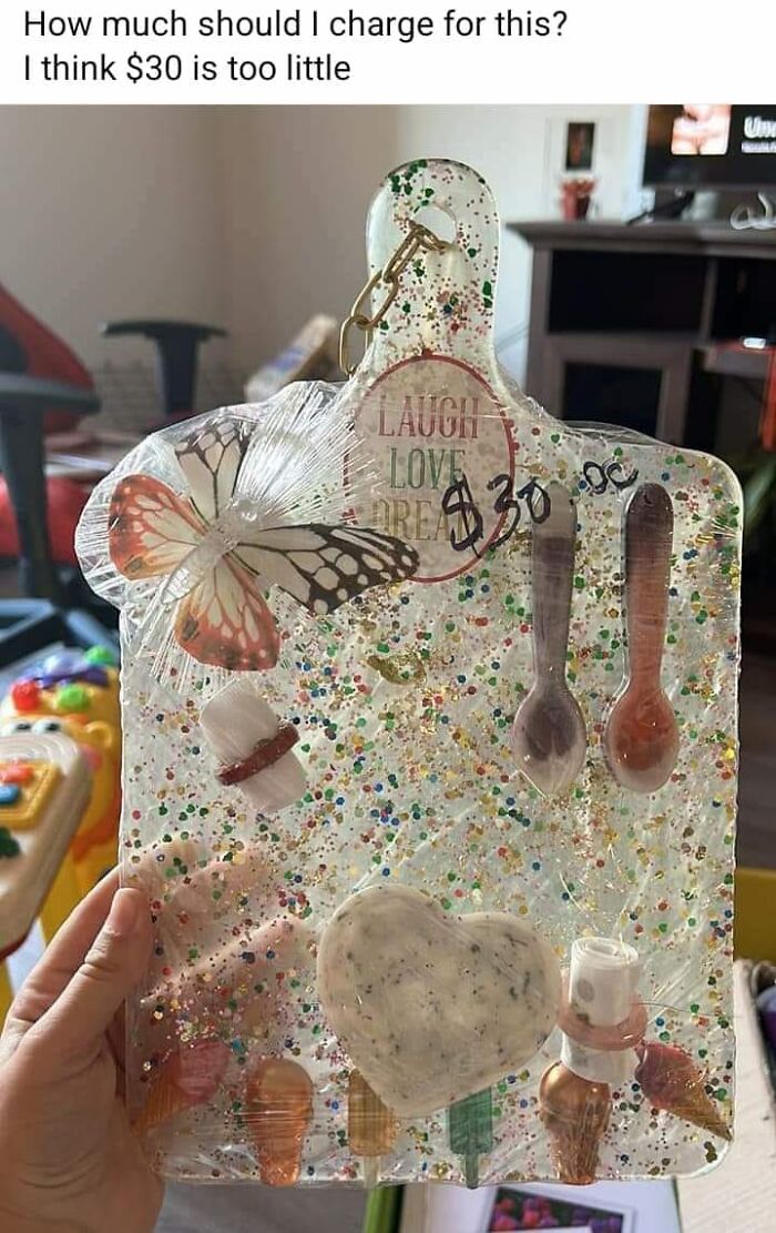 Horrendous DIY project with glitter, butterfly, spoons, and price tag, held in hand for pricing advice.