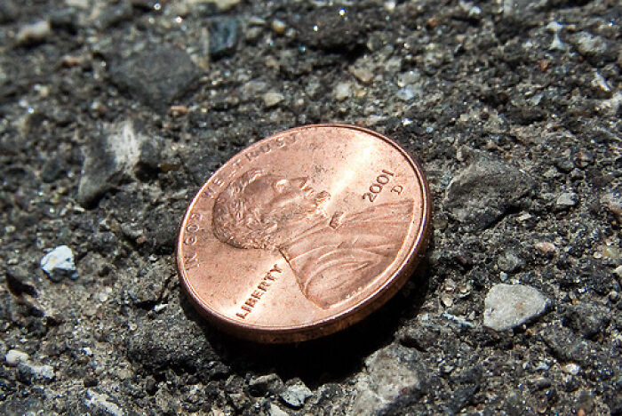 Coin on asphalt related to a superstition discussion in a forum post.