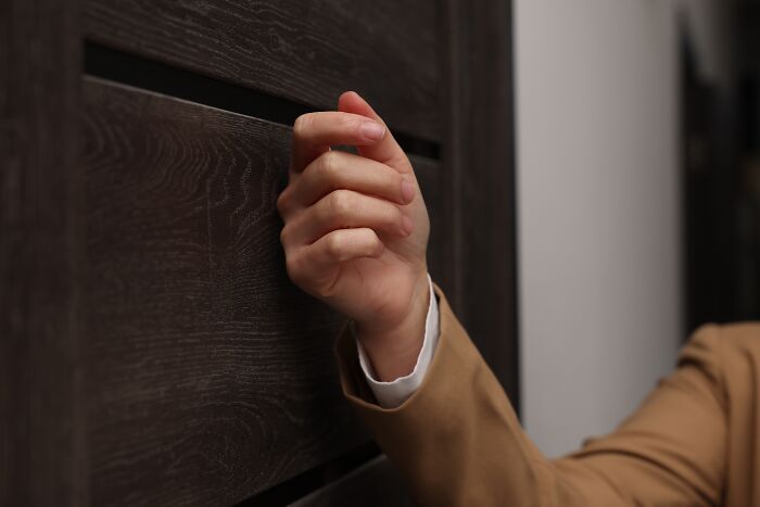 Hand knocking on a wooden door, symbolizing unexpected visit and potential rejection. Hand knocking on a wooden door, symbolizing unexpected visit and potential rejection.