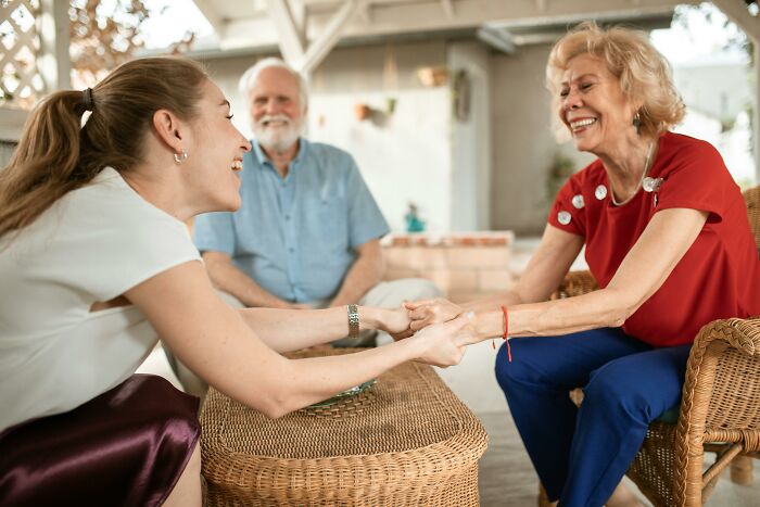 Mother-in-law smiling during a visit to son's home, holding hands with daughter-in-law outside. Mother-in-law smiling during a visit to son's home, holding hands with daughter-in-law outside.