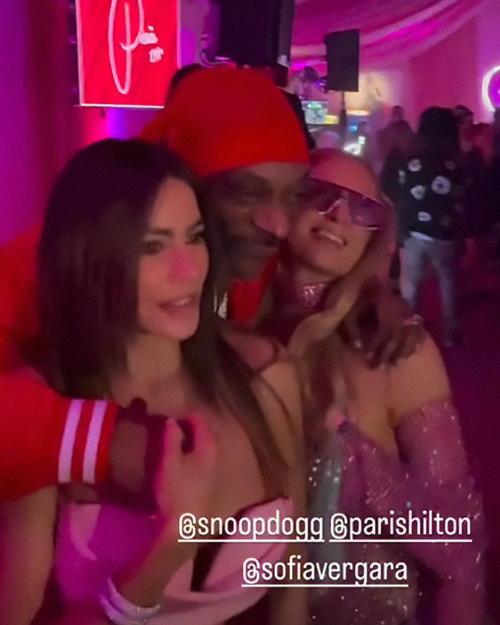 Sofia Vergara, Snoop Dogg, and Paris Hilton posing together with colorful lights and a branded backdrop.