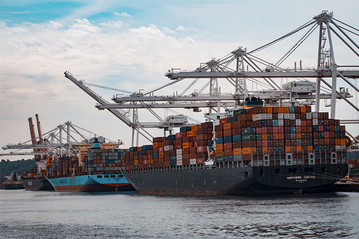 Cargo ships loaded with containers docked at a busy port, highlighting critical logistics operations and shipments.