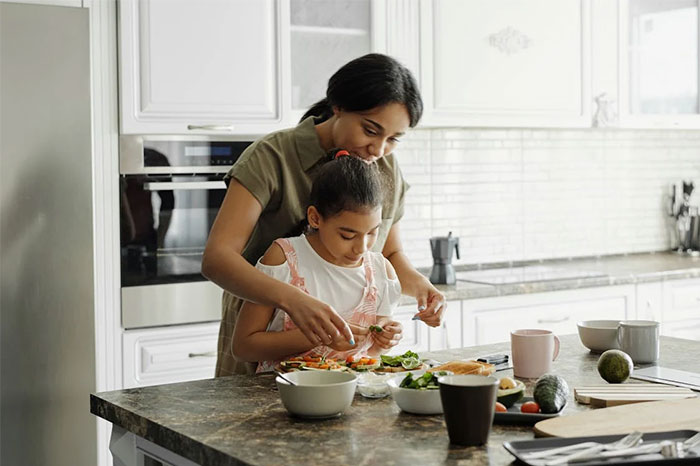 Mother and daughter cooking together in a modern kitchen, focusing on critical life skills.