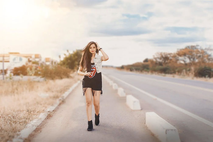 Woman walking confidently down an empty road, demonstrating critical life skills under an expansive sky.