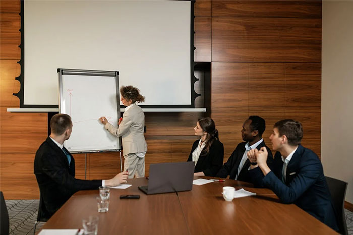 A person in a suit presenting critical things on a flip chart to colleagues in a conference room.
