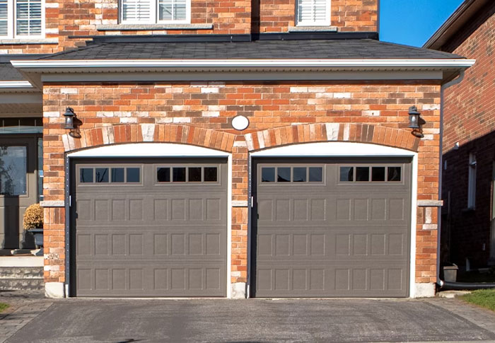 Brick house with two brown garage doors, under a clear blue sky. Critical home feature often overlooked.