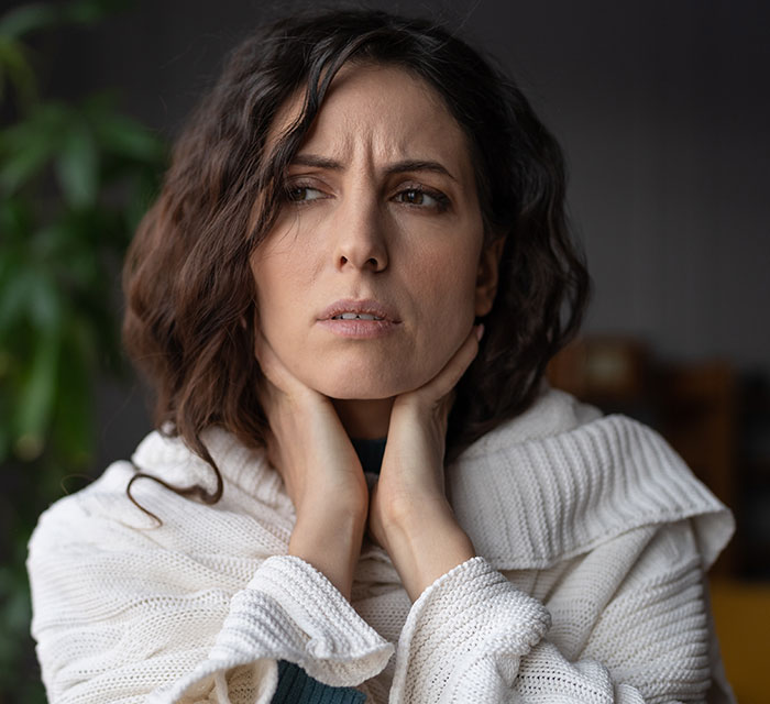 A concerned parent in a white sweater, reflecting on unexpected party guests.