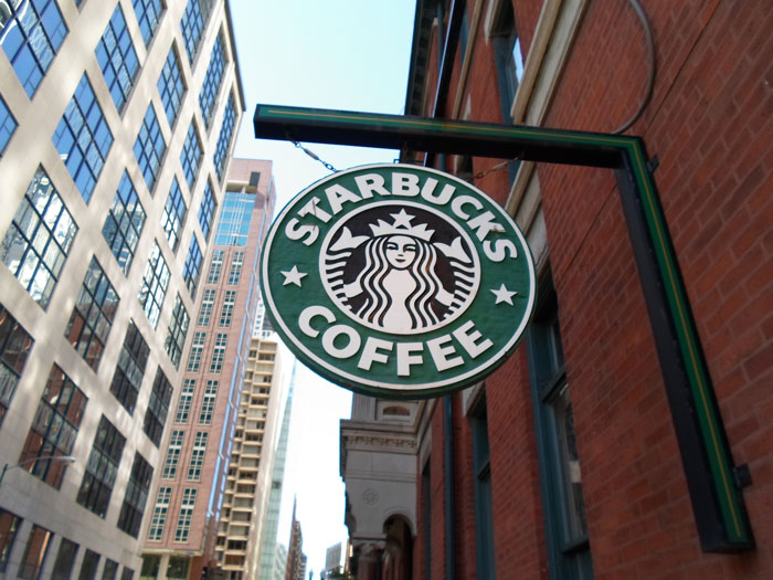 Starbucks sign hanging outside a brick building, hinting at a menu update with 13 drinks. Starbucks sign hanging outside a brick building, hinting at a menu update with 13 drinks.