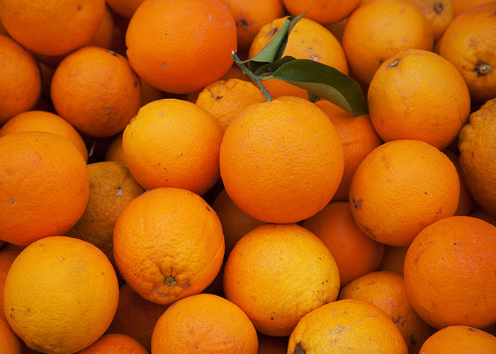 Oranges piled together, with one featuring a green leaf. Hotel housekeepers might find this strange in a room.