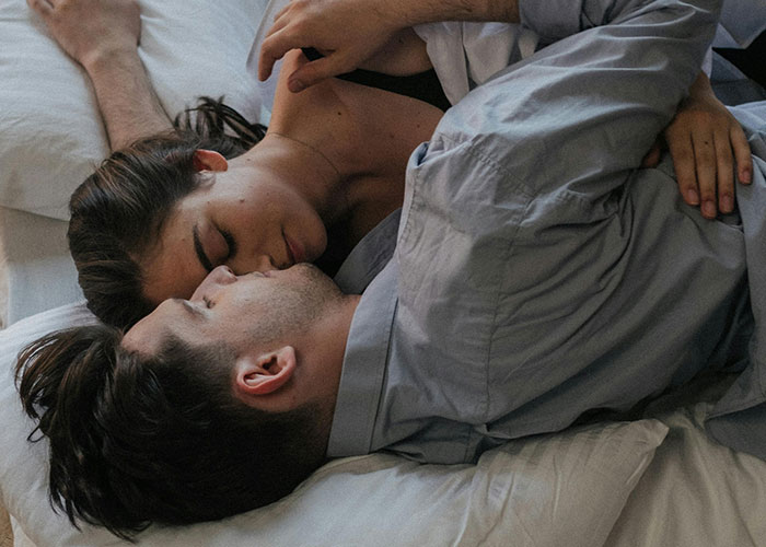 Couple cuddling in bed, capturing an intimate moment in a hotel room setting.