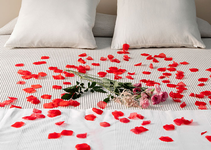 Rose petals and a bouquet on a hotel bed, creating a romantic setting seen by housekeepers.