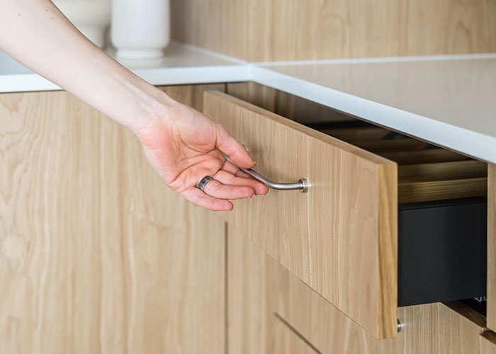 Person opening a wooden drawer in a hotel room.