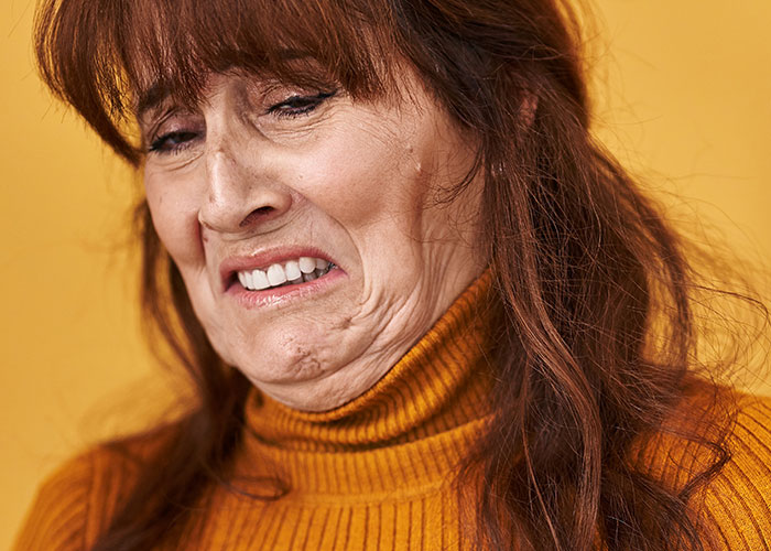 A woman in a mustard sweater making a disgusted face, possibly reacting to something strange found by hotel housekeepers.
