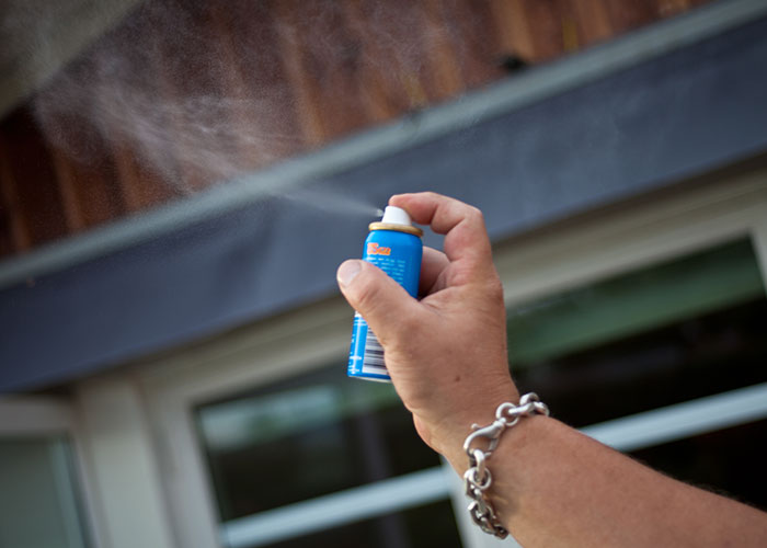 Hand spraying air freshener outside a hotel room.