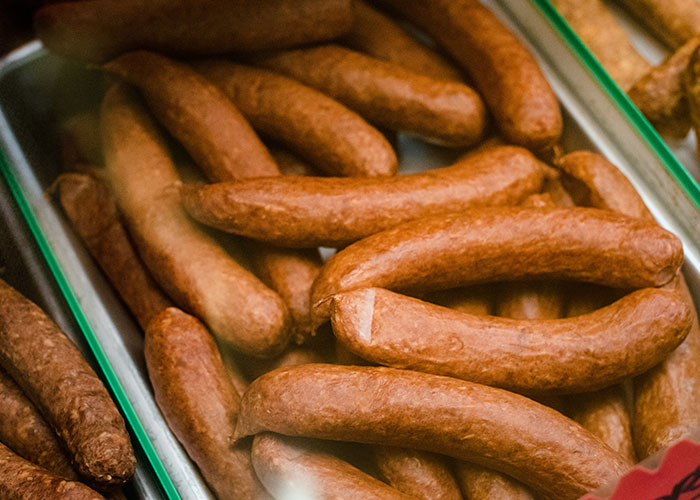 Tray filled with multiple sausages under a display light.