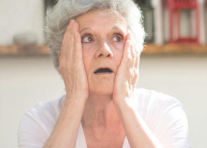 Surprised woman with hands on face, possibly reacting to a strange hotel room discovery.