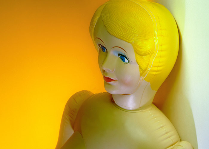 Inflatable doll with yellow hair against a bright background, related to hotel housekeepers' strange room encounters.
