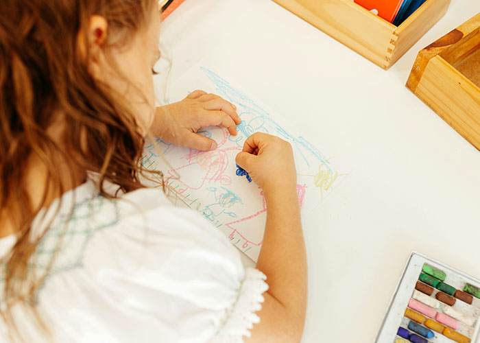 Child drawing with crayons on paper, related to strange punishment stories.