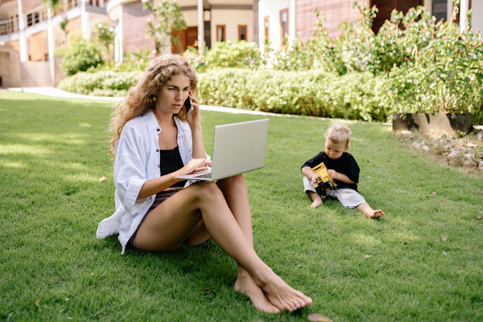 Woman on laptop with child playing outside, related to private home tour theme. Woman on laptop with child playing outside, related to private home tour theme.