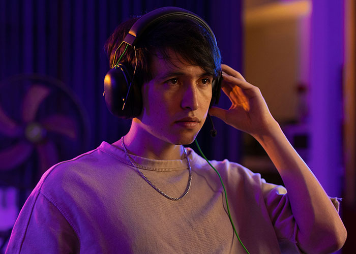 Person with headphones, focused and adjusting them, in a dimly lit room.