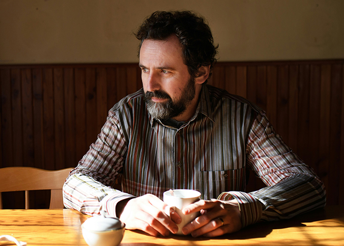 A man sitting at a table with a coffee cup, representing an uncle's concern for his nephew.