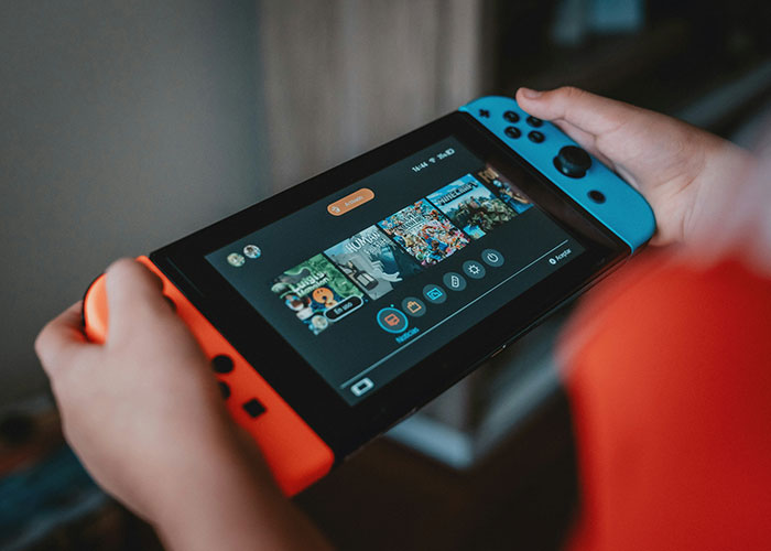 Child holding a Nintendo Switch, gaming menu visible on screen, representing family dynamics and boundaries.